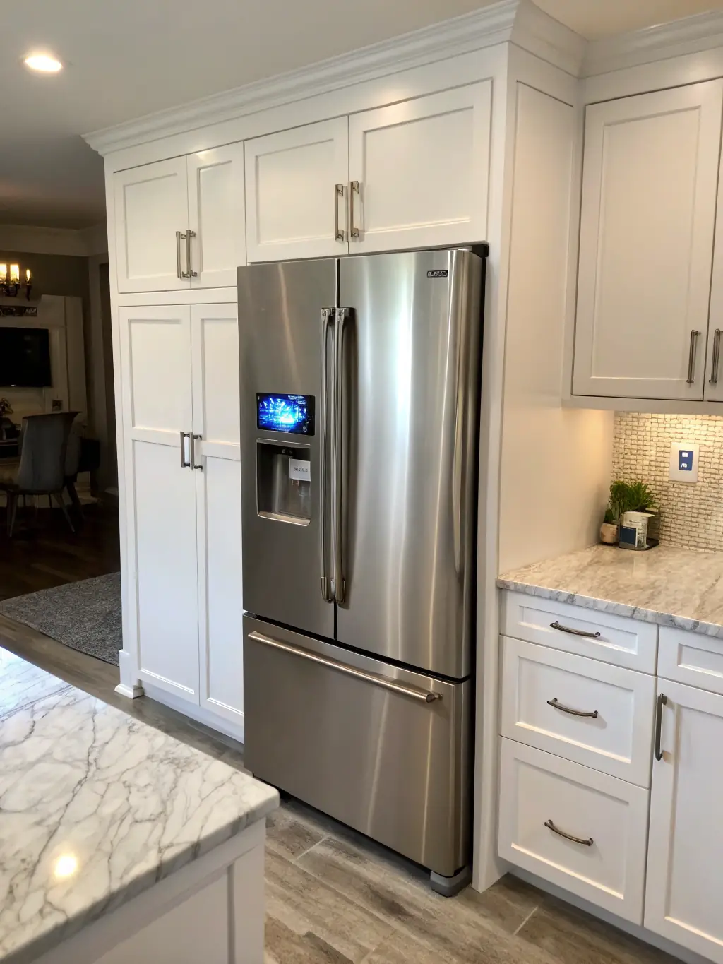 A modern kitchen featuring a built-in Sub-Zero refrigerator with a technician in uniform carefully inspecting the door seal.